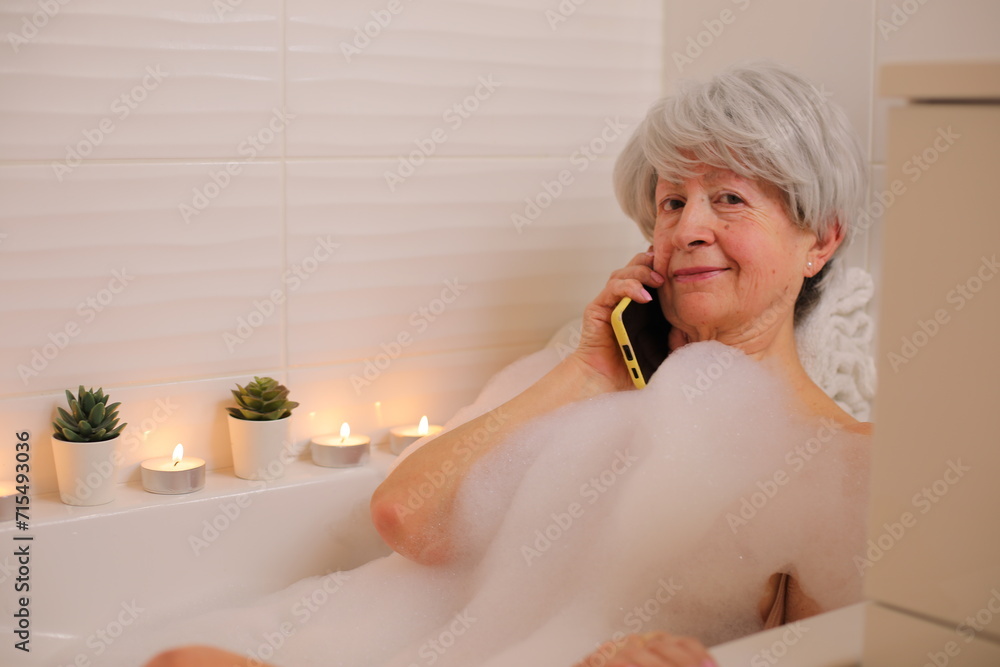 Relaxed senior woman making a phone call in the bathtub Relaxed senior woman making a phone call in the bathtub