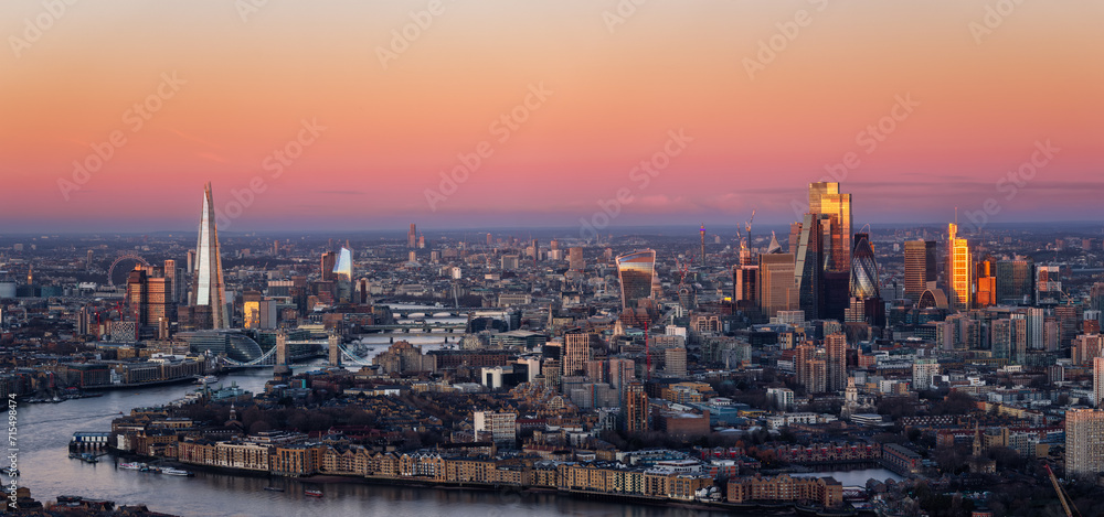 Wide panoramic view of the London skyline during dawn with pink colors and soft sunlight reflecting from the City skyscrapers, England
