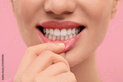 Beautiful woman showing her clean teeth on pink background  closeup