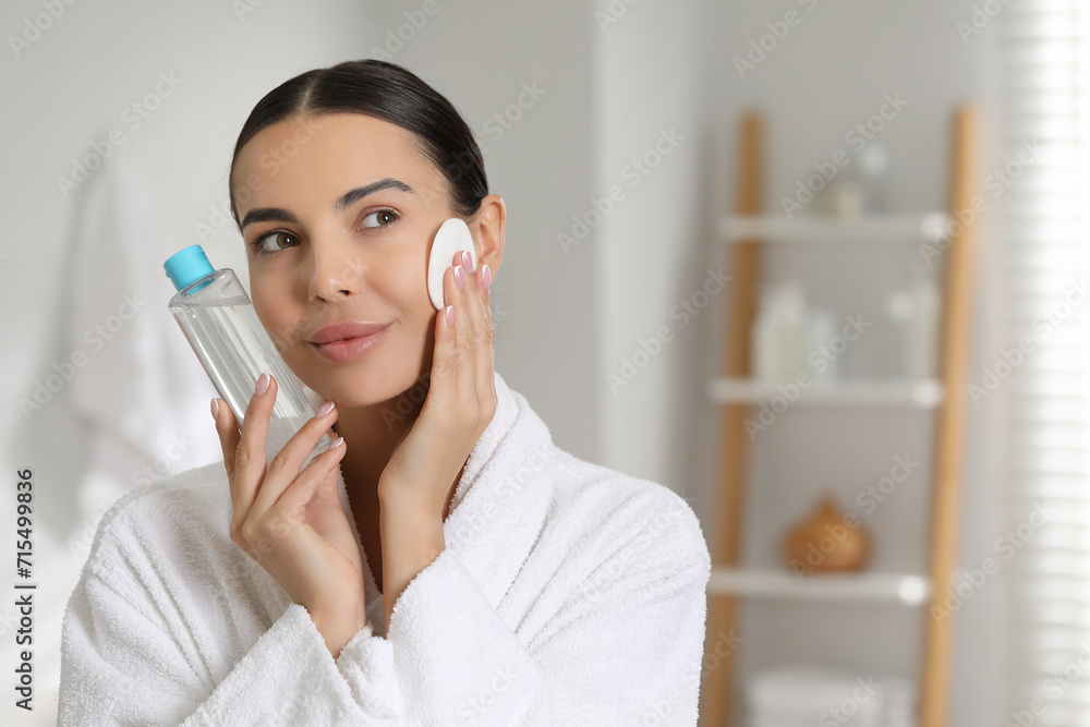 Beautiful woman removing makeup with cotton pad in bathroom, space for text Beautiful woman removing makeup with cotton pad in bathroom, space for text
