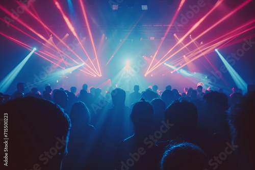 Audience at a night club with red and blue laser beams and fog