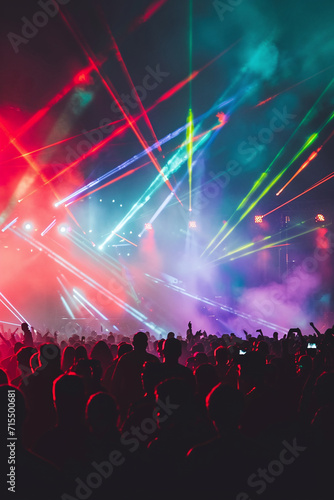 Concert crowd enjoying a music festival with colorful stage lights and laser show © Qmini
