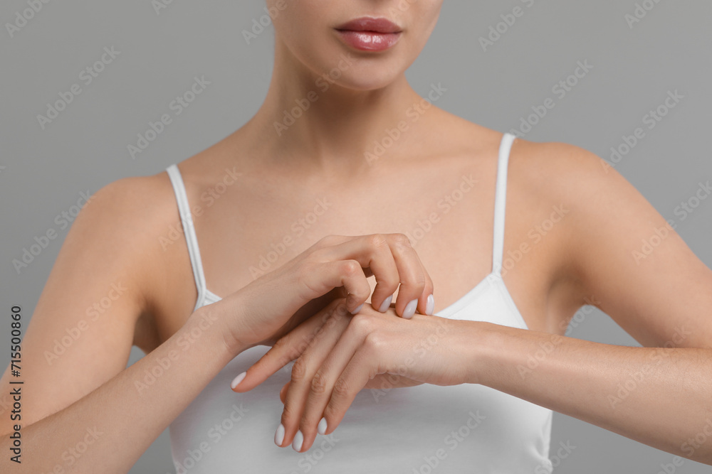 Woman with dry skin checking her arm on gray background, closeup