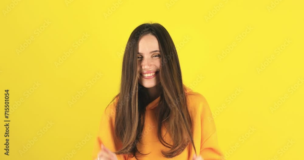 Young beautiful happy girl in cozy yellow hoody thoughtfully examining ends of her hair over yellow background, she like quality of her hair, she smiling. Young beautiful happy girl in cozy yellow hoody thoughtfully examining ends of her hair over yellow background, she like quality of her hair, she smiling.