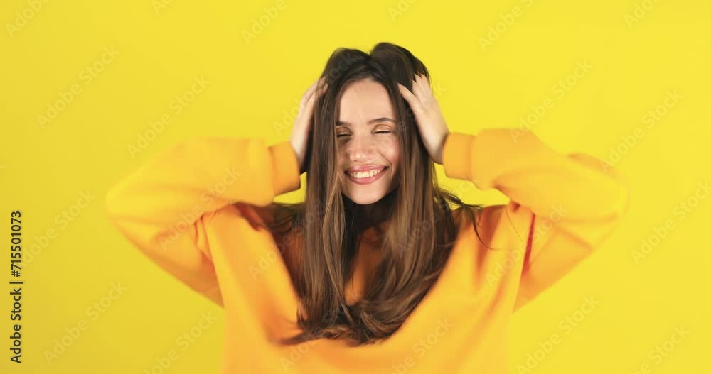 Cheerful happy joyful young woman wear yellow hoody, brunette loose hair cheerfully throws. Smiling face. Happy woman fix hair, look funny and funky isolated on yellow background. Cheerful happy joyful young woman wear yellow hoody, brunette loose hair cheerfully throws. Smiling face. Happy woman fix hair, look funny and funky isolated on yellow background.