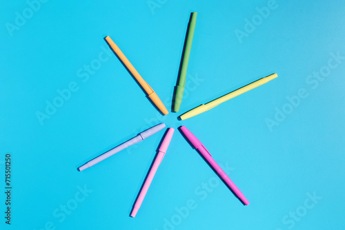 Multicolored ballpoint pens on a blue background. Back to school. Stylish stationery.