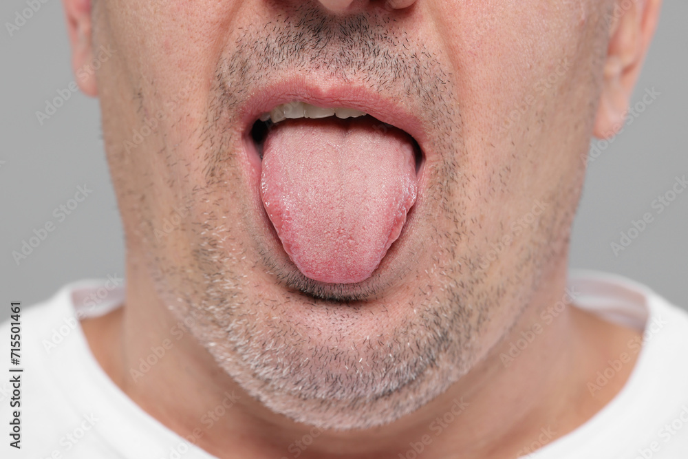 Man showing his tongue on grey background, closeup Man showing his tongue on grey background, closeup