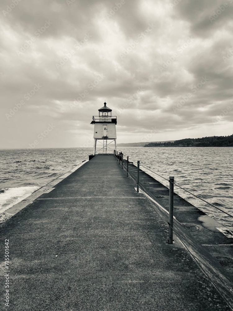 black and white photo of a lighthouse with a pier on the edge