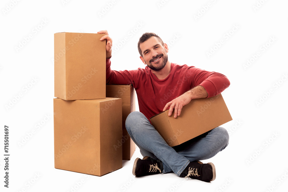 Smiling seated man with beard and red sweater on white background surrounded by large cardboard boxes. Home delivery service. Moving help service. Free shipping Smiling seated man with beard and red sweater on white background surrounded by large cardboard boxes. Home delivery service. Moving help service. Free shipping