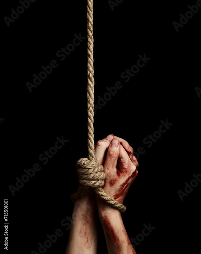 Woman's hands with bloody stains tied with a rope over black background