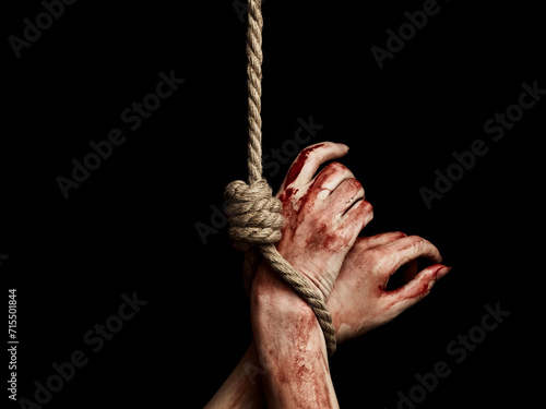 Woman's hands with bloody stains tied with a rope over black background