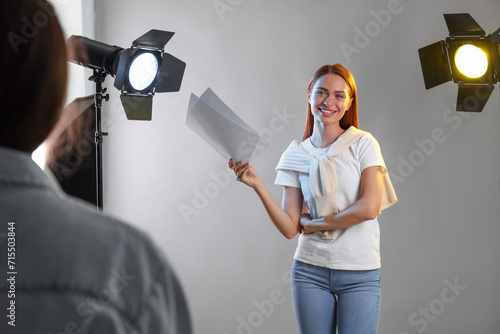 Young woman with script in front of casting director against grey background at studio photo