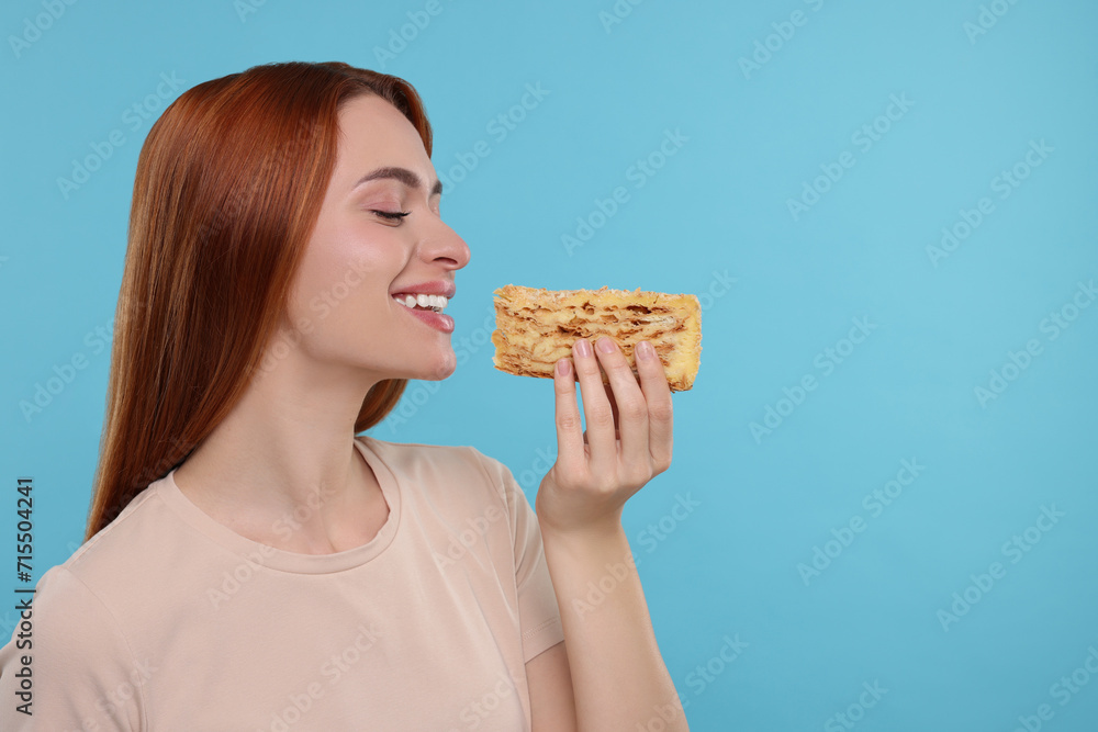 Young woman with tasty cake on light blue background, space for text Young woman with tasty cake on light blue background, space for text