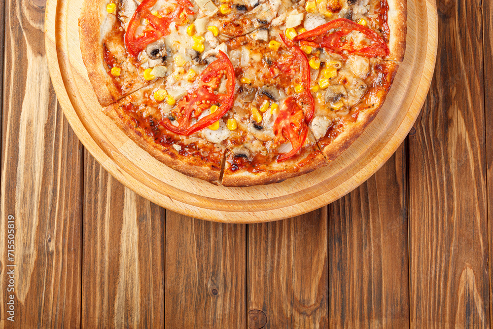 delicious pizza with chicken, mushrooms, cheese, tomatoes and corn on a wooden background delicious pizza with chicken, mushrooms, cheese, tomatoes and corn on a wooden background