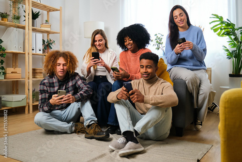 Group of young flat mates using their smartphone together at shared apartment.