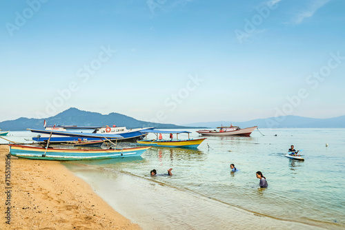 Locals swimming at the town beach with mainland beyond on this coral fringed holiday island, Bunaken Island, Sulawesi, Indonesia, Southeast Asia photo