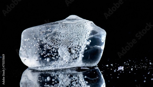 crystal clear natural ice block withr bubbles and cracks on black reflective surface