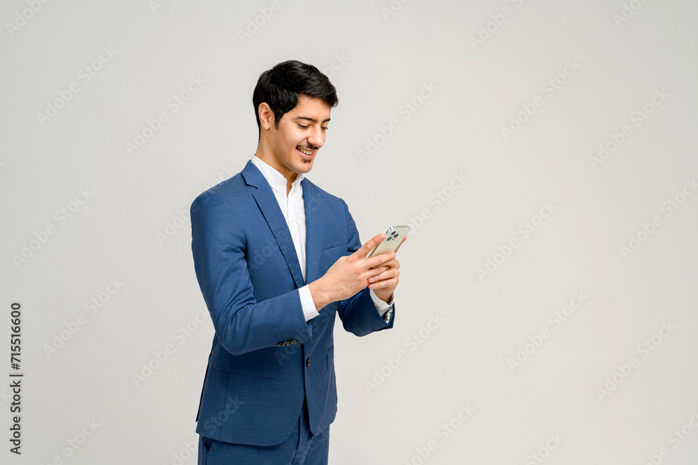 A well-dressed professional man in a blue suit exudes charm while using smartphone, indicative of modern business practices and connectivity A well-dressed professional man in a blue suit exudes charm while using smartphone, indicative of modern business practices and connectivity
