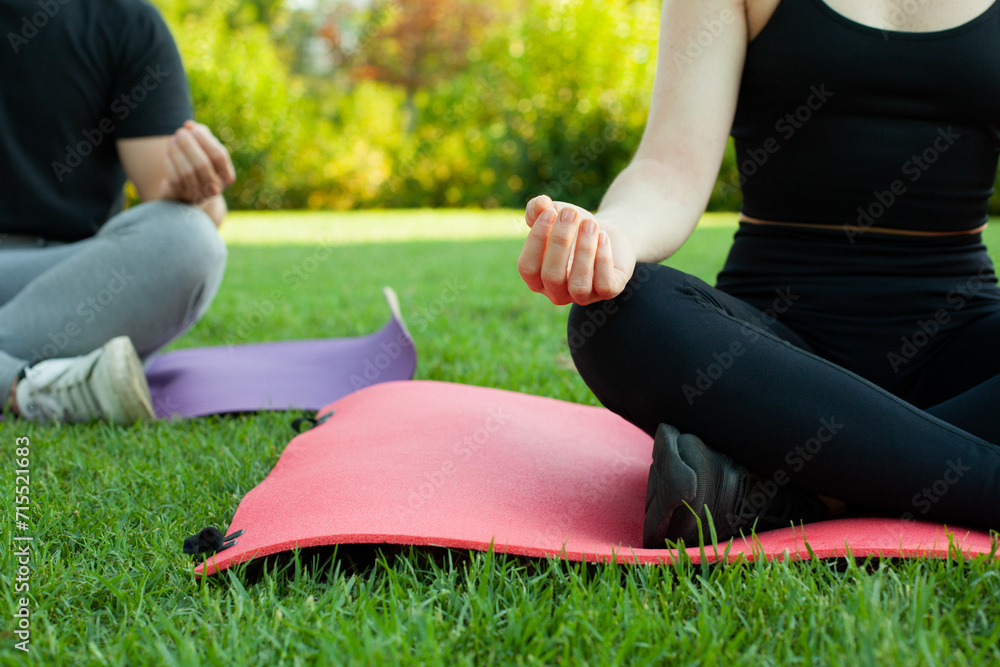 Pareja de chico y chica haciendo yoga en el parque al aire libre. Deporte con esterillas. Descanso en esterilla. Estilo de vida saludable. Pareja de chico y chica haciendo yoga en el parque al aire libre. Deporte con esterillas. Descanso en esterilla. Estilo de vida saludable.