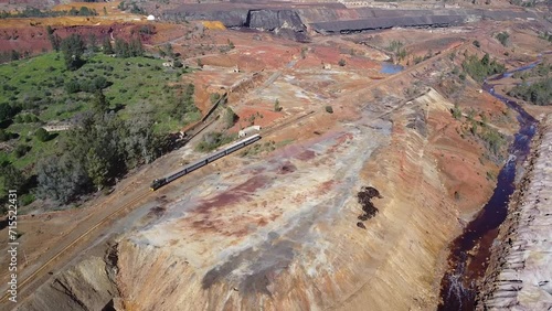Aerial drone view of the old tourist train on a tour of the remains of the copper mine exploitation named Corta Atalaya, in the town of Minas de Riotinto in the province of Huelva