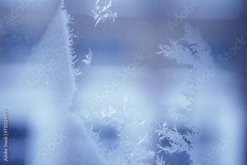 Close up of an abstract blurred freezing patterns on the glass window with copy space. Blue blurred background.