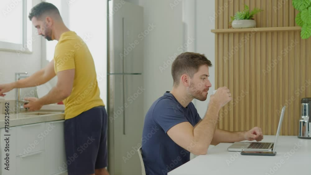 Gay couple. Freelancer working online at laptop and taking notes. indoor at kitchen home. language learning, online education, work concept.
Gay couple. Freelancer working online at laptop and taking notes. indoor at kitchen home. language learning, online education, work concept.
