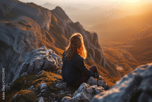 Red-haired girl in the mountains looking at the sunset. Travel and adventures