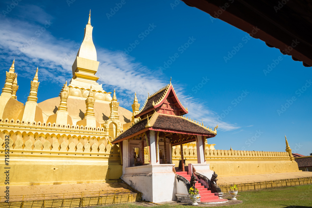 Naklejka premium Beautiful large golden pagoda Pha That Luang temple famous landmark in Vientiane, Laos PDR sunny day blue sky background. Travel destination and religion in Asia concept.