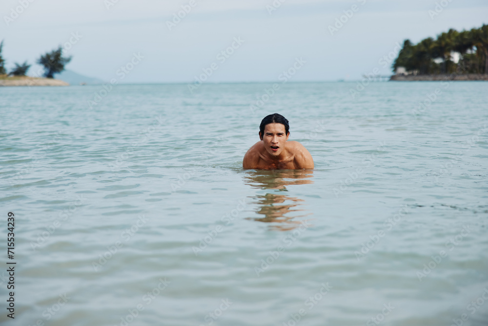 Smiling Asian Man Enjoying a Tropical Swim in the Blue Ocean