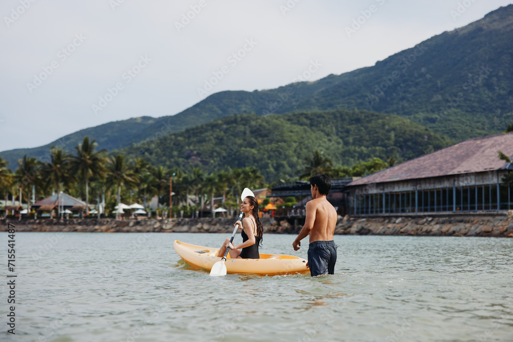 Kayaking Harmony: A Joyful Asian Couple Paddling in the Serene Tropical Waters