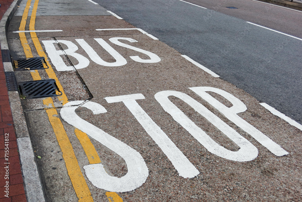 Fototapeta premium white bus stop words sign painted on the road with two yellow lines along the pavement 