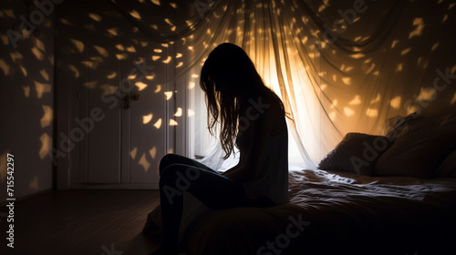silhouette of woman sitting on the bed beside the windows with sunlight in the morning photo