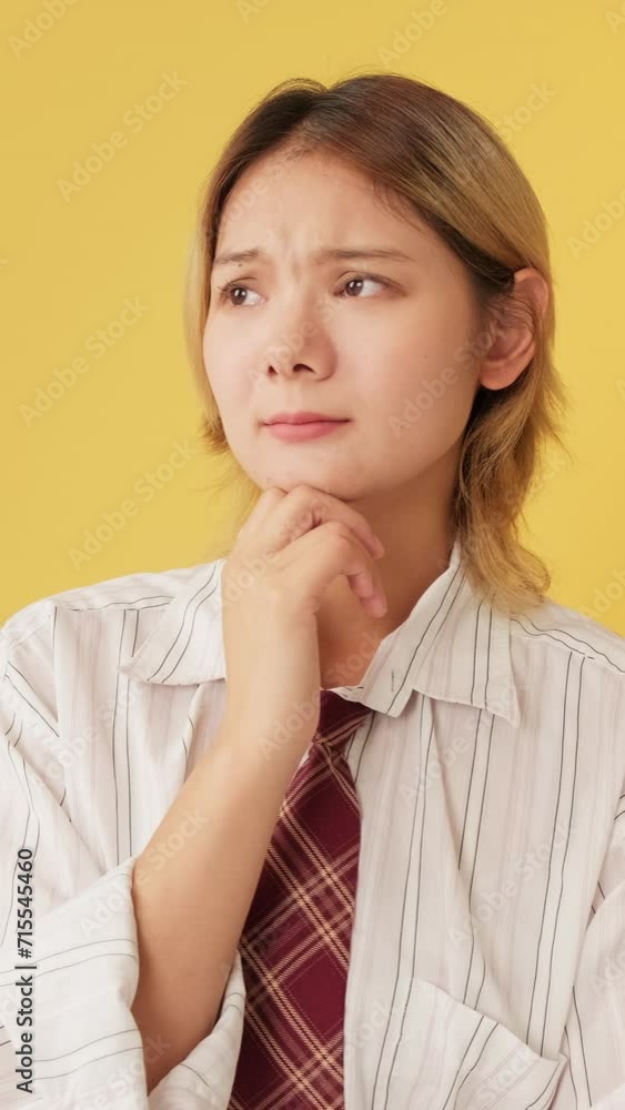 Young woman thinks over problem, remembering something isolated on yellow background in studio Young woman thinks over problem, remembering something isolated on yellow background in studio