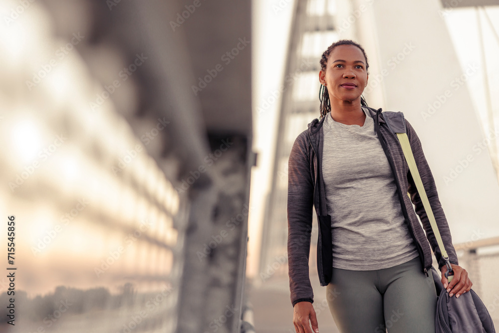 Woman carrying gym bag while going for an outdoor workout Woman carrying gym bag while going for an outdoor workout