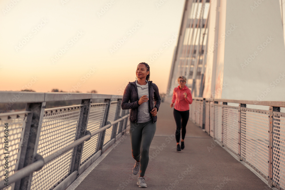 Women jogging over the bridge at dawn