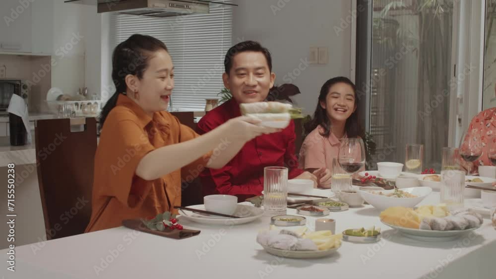 Multi-generational Asian family dining at festive table in cozy living room Multi-generational Asian family dining at festive table in cozy living room