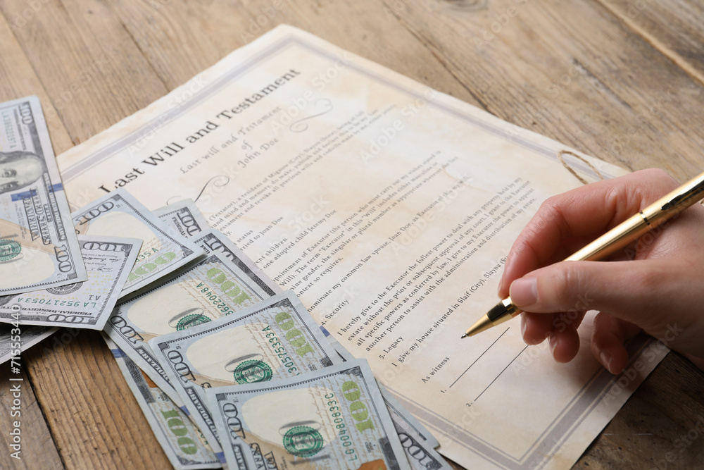 Obraz premium Woman signing Last Will and Testament at wooden table, closeup