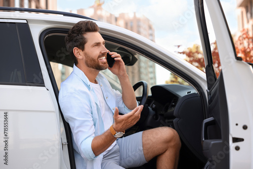 Happy man talking on smartphone in modern car