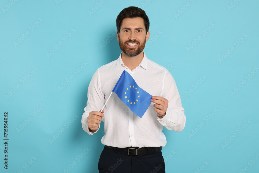 Man with flag of European Union on light blue background Man with flag of European Union on light blue background