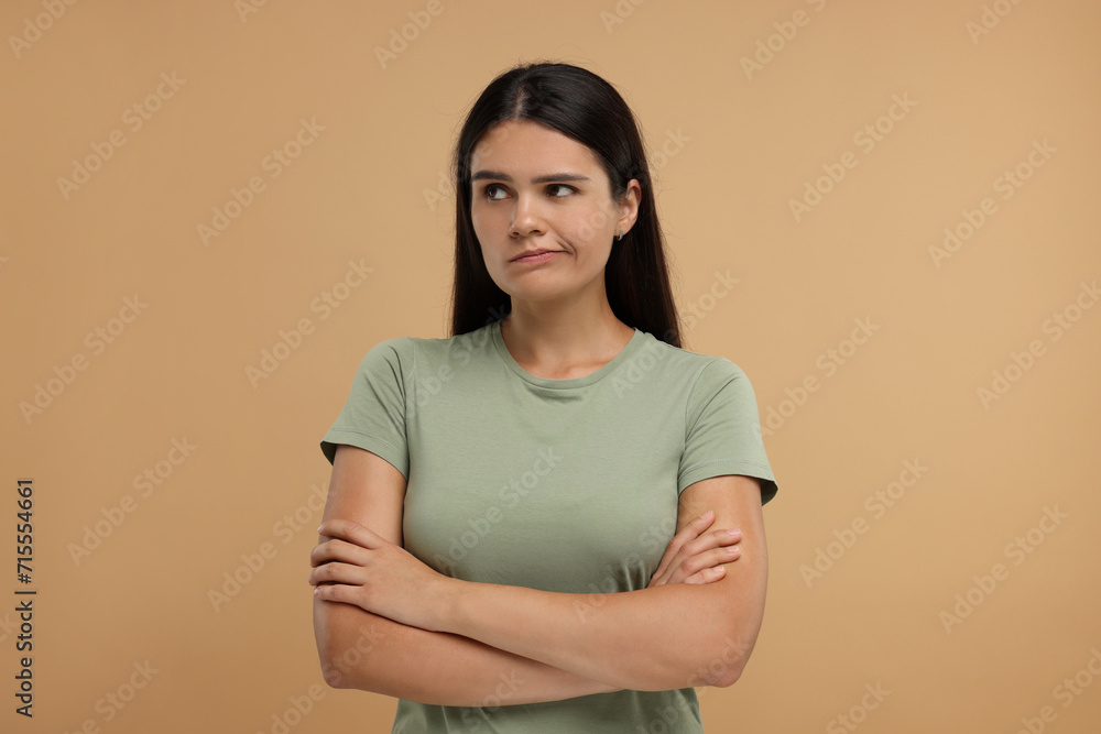 Portrait of resentful woman with crossed arms on beige background Portrait of resentful woman with crossed arms on beige background