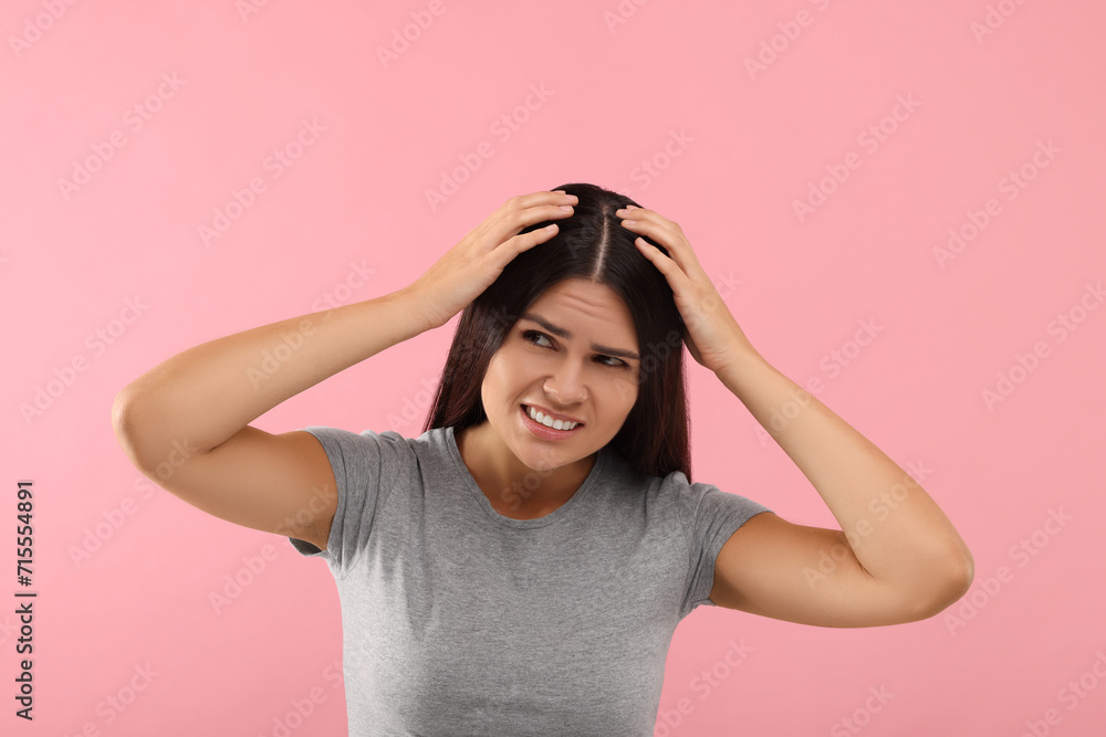 Emotional woman examining her hair and scalp on pink background Emotional woman examining her hair and scalp on pink background