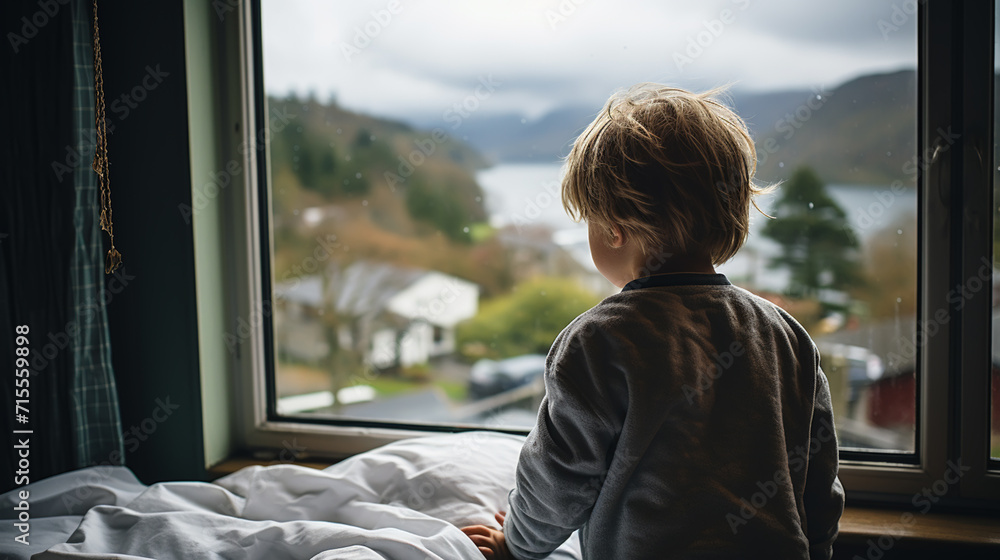 Fototapeta premium Back view of kid patient sitting on hospital bed looking out of window. Preteen sick boy sitting on bed in hospital ward.
