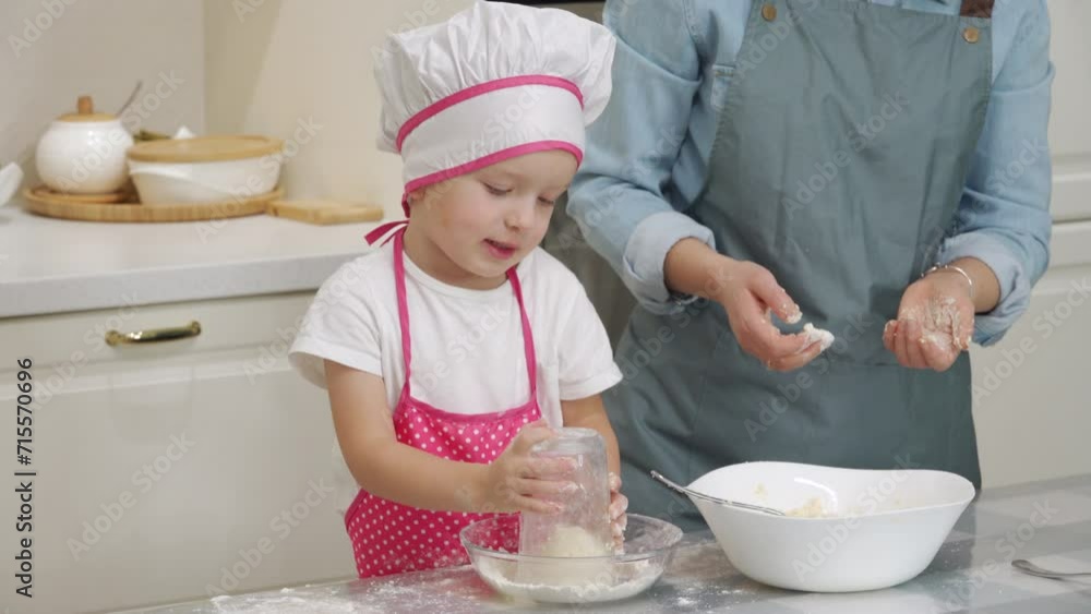 Mother with child preparing dinner together in modern kitchen at home, little boy in chef uniform helping mom cooking fried quark pancakes Syrniki. Belarusian, Russian, Ukrainian cuisine. Mother with child preparing dinner together in modern kitchen at home, little boy in chef uniform helping mom cooking fried quark pancakes Syrniki. Belarusian, Russian, Ukrainian cuisine.