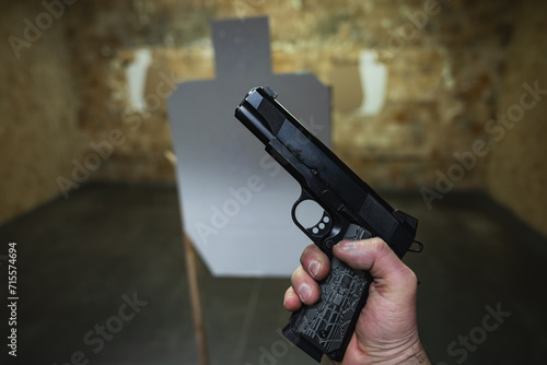 M1911 pistol in a man's hand at a shooting range.