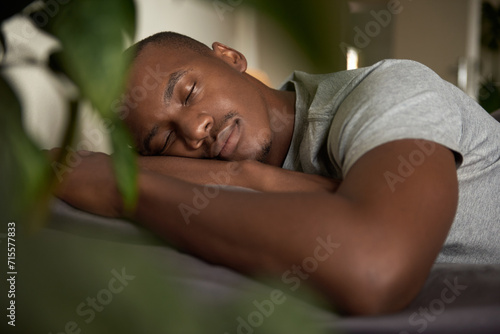 Young African man sleeping in his bed at home