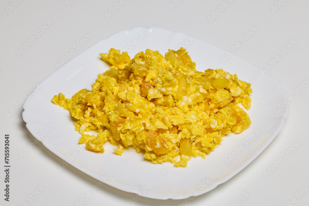 a plate of scrambled eggs on a table ready to be eaten.