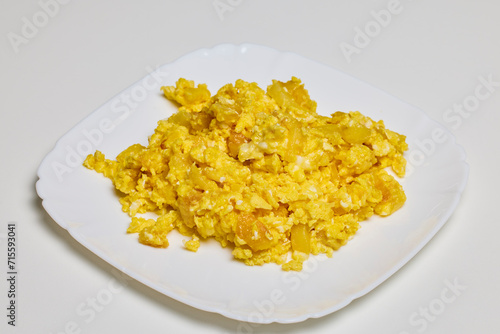a plate of scrambled eggs on a table ready to be eaten.