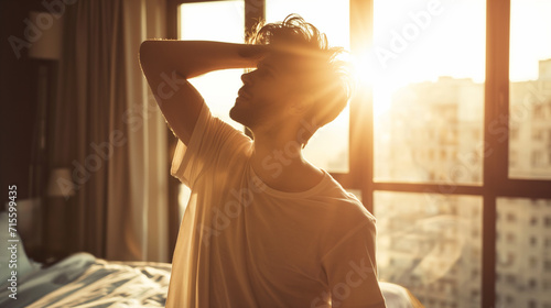 Homem acordando em sua cama e se espreguiçando ao nascer do sol  photo