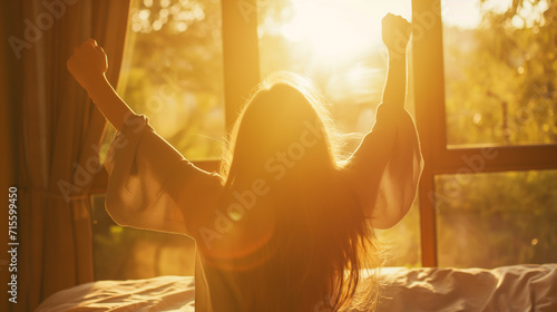 Mulher acordando em sua cama e se espreguiçando ao nascer do sol photo