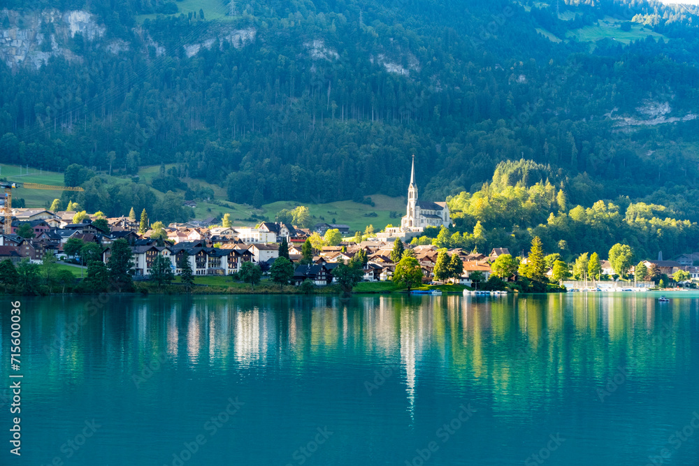 Fototapeta premium Swiss village Lungern with traditional houses, old church Alter Kirchturm along lovely emerald green lake Lungerersee, canton of Obwalden Switzerland